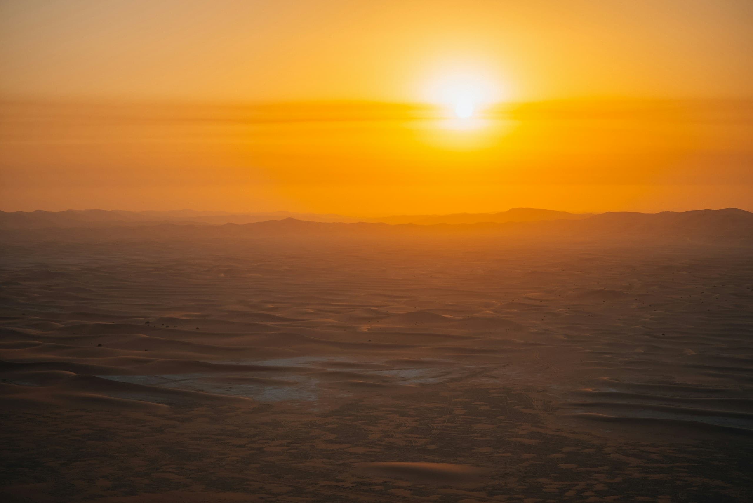 Golden sun setting over hazy dunes